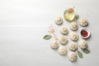 Photo of Uncooked khinkalis (dumplings) and spices on white wooden table, flat lay. Space for text