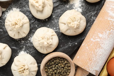 Photo of Uncooked khinkalis (dumplings), flour, spices and rolling pin on table, flat lay