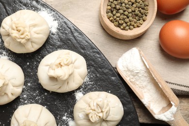 Photo of Uncooked khinkalis (dumplings), flour, spices and eggs on table, flat lay