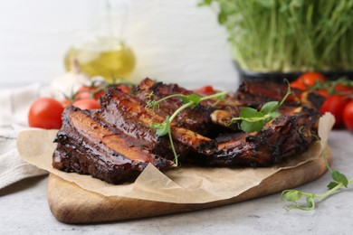 Photo of Roasted beef ribs with microgreens on gray textured table, closeup