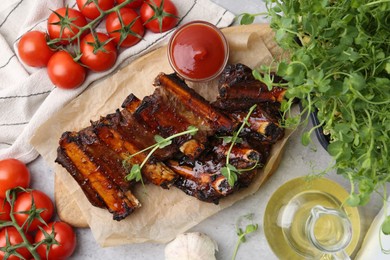 Photo of Roasted beef ribs with microgreens, tomatoes and other products on table, flat lay
