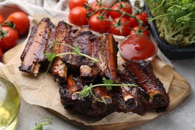 Photo of Roasted beef ribs with microgreens, tomatoes and sauce on table, closeup