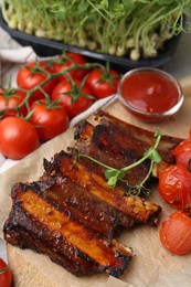 Photo of Roasted beef ribs with microgreens, tomatoes and sauce on table, closeup