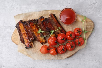 Photo of Roasted beef ribs with microgreens, tomatoes and sauce on gray textured table, top view