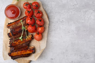 Photo of Roasted beef ribs with microgreens, tomatoes and sauce on gray textured table, top view. Space for text
