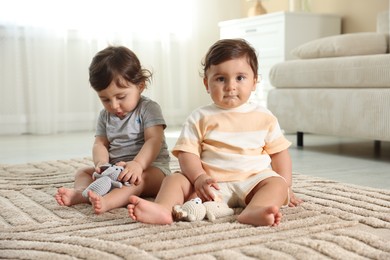 Photo of Cute little twin babies playing with toys on floor at home