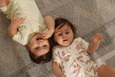 Photo of Cute little twin babies on floor at home, above view