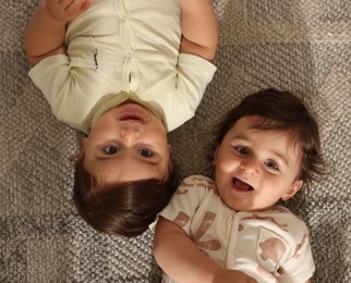Photo of Cute little twin babies on floor at home, above view