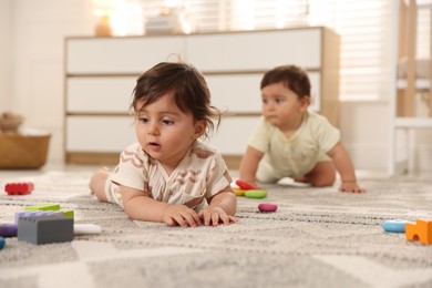 Photo of Cute little twin babies playing with toys on floor at home, selective focus