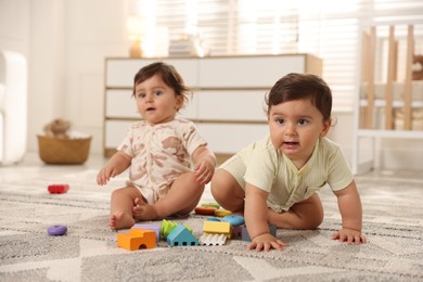 Photo of Cute little twin babies playing with toys on floor at home