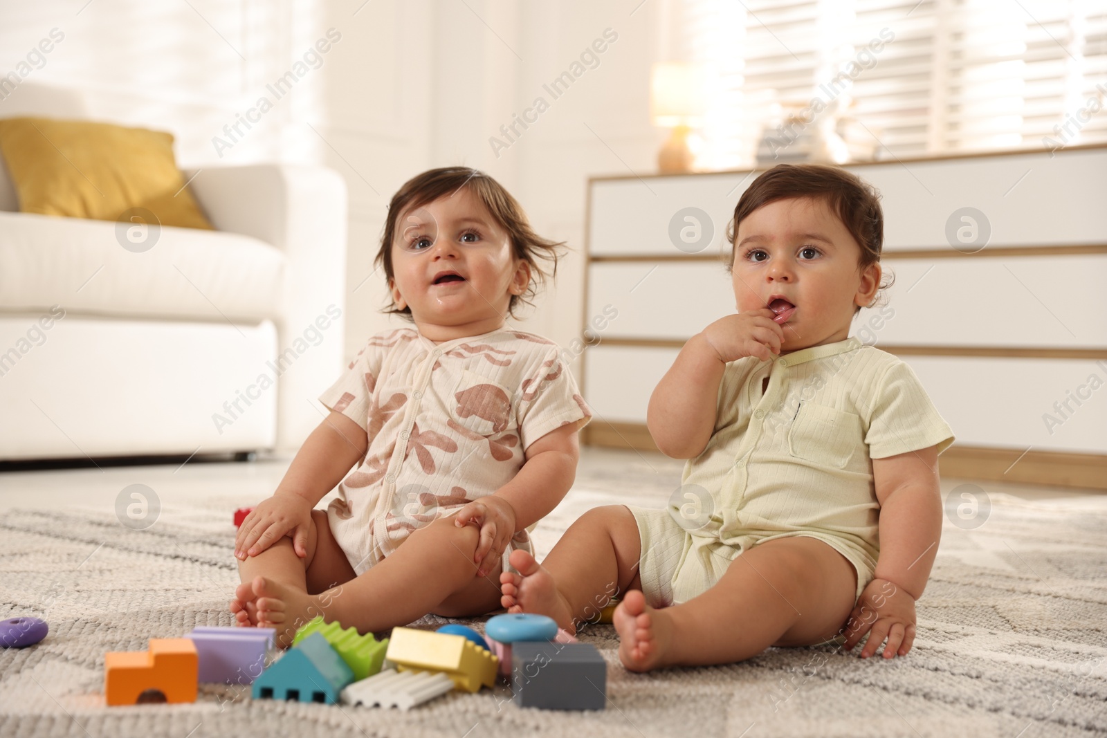 Cute little twin babies playing with toys on floor at home Photo of Cute little twin babies playing with toys on floor at home