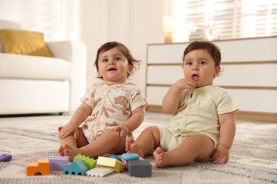 Photo of Cute little twin babies playing with toys on floor at home