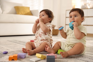 Photo of Cute little twin babies playing with toys on floor at home