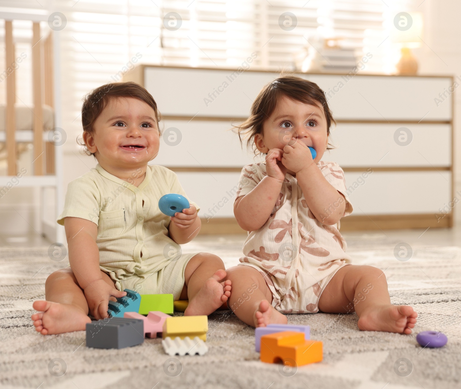 Cute little twin babies playing with toys on floor at home Photo of Cute little twin babies playing with toys on floor at home