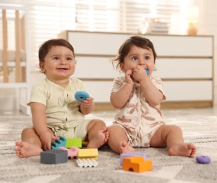Photo of Cute little twin babies playing with toys on floor at home