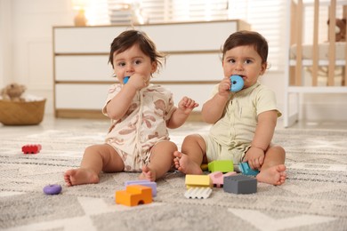 Photo of Cute little twin babies playing with toys on floor at home