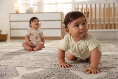 Photo of Cute little twin babies on floor at home, selective focus