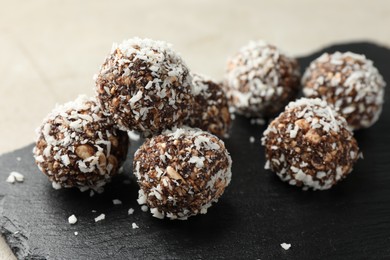 Photo of Tasty chocolate candies with nuts and coconut flakes on light table, closeup
