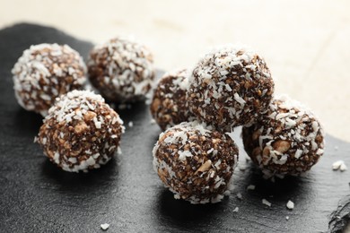 Photo of Tasty chocolate candies with nuts and coconut flakes on light table, closeup