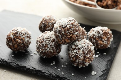 Photo of Tasty chocolate candies with nuts and coconut flakes on light table, closeup