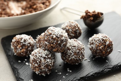 Photo of Tasty chocolate candies with nuts and coconut flakes on light table, closeup