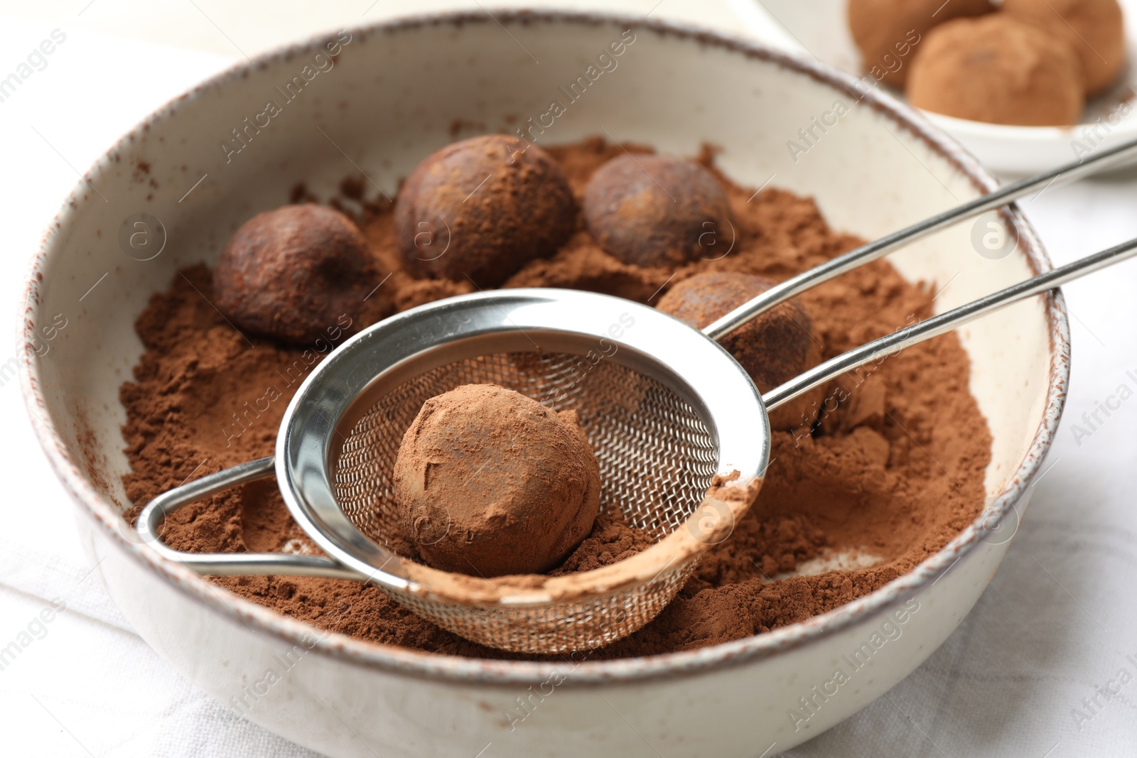 Making tasty chocolate candies with cocoa powder at light table, closeup Photo of Making tasty chocolate candies with cocoa powder at light table, closeup