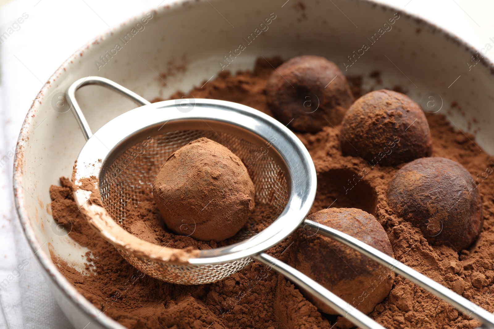 Making tasty chocolate candies with cocoa powder at light table, closeup Photo of Making tasty chocolate candies with cocoa powder at light table, closeup