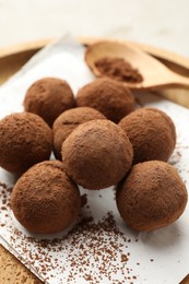 Photo of Tasty chocolate candies with cocoa powder on light table, closeup