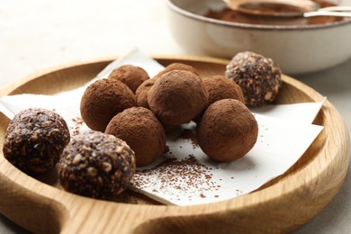 Photo of Tasty chocolate candies with cocoa powder on light table, closeup