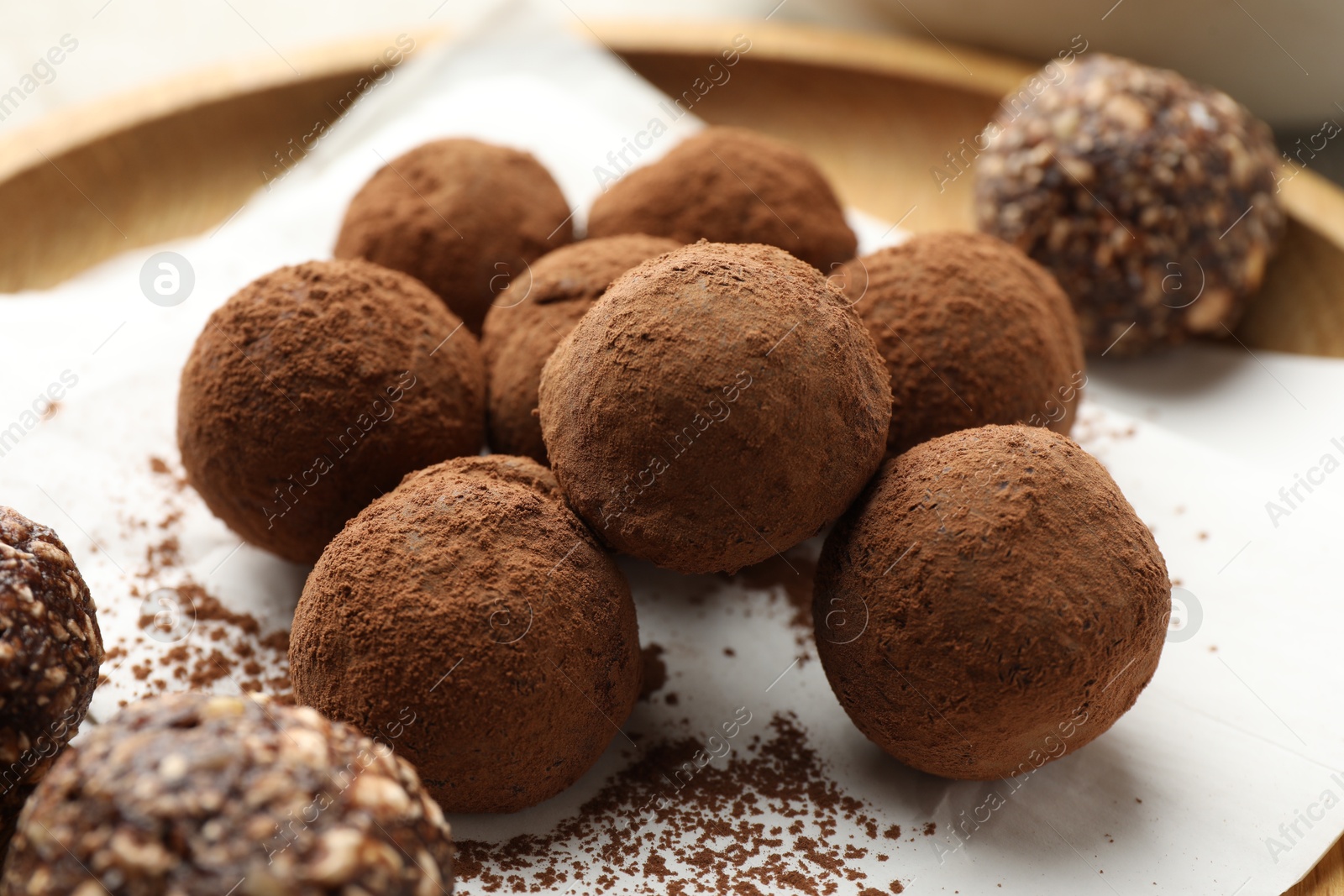 Tasty chocolate candies with cocoa powder on light table, closeup Photo of Tasty chocolate candies with cocoa powder on light table, closeup
