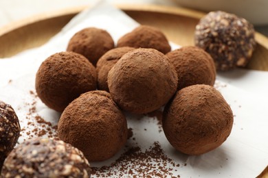 Photo of Tasty chocolate candies with cocoa powder on light table, closeup