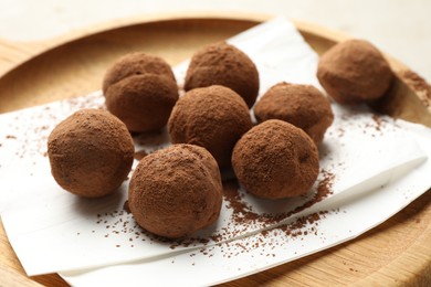 Photo of Tasty chocolate candies with cocoa powder on light table, closeup