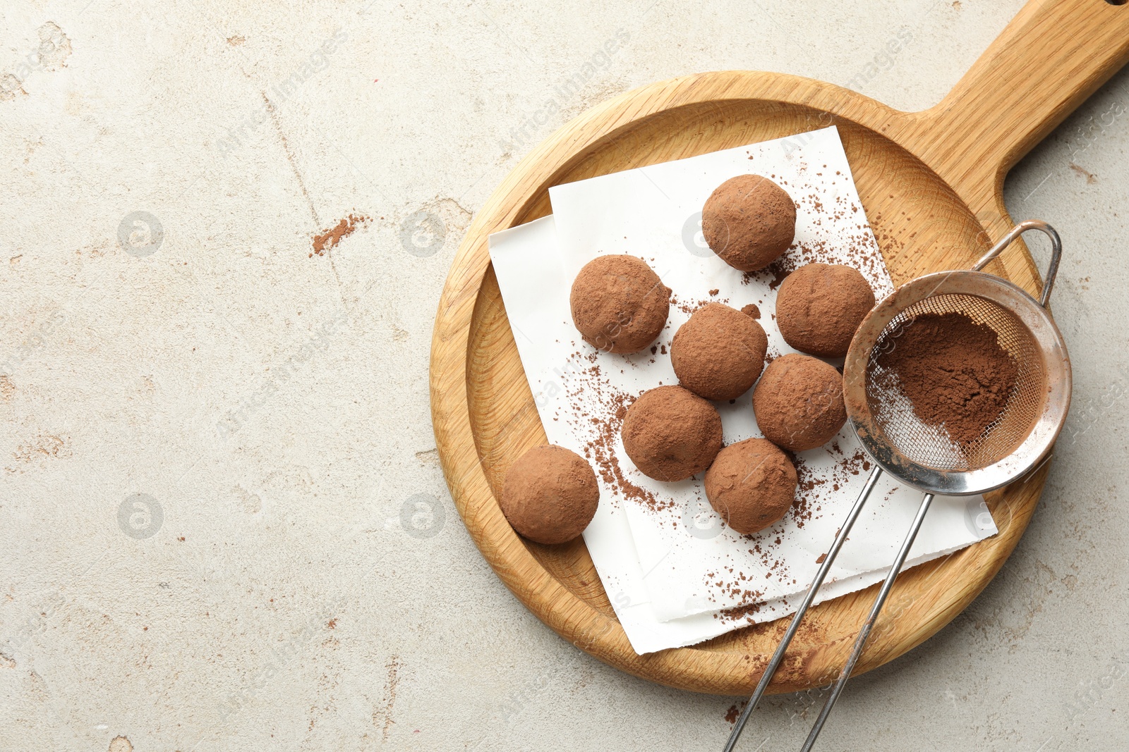 Tasty chocolate candies with cocoa powder and strainer on light table, top view. Space for text Photo of Tasty chocolate candies with cocoa powder and strainer on light table, top view. Space for text