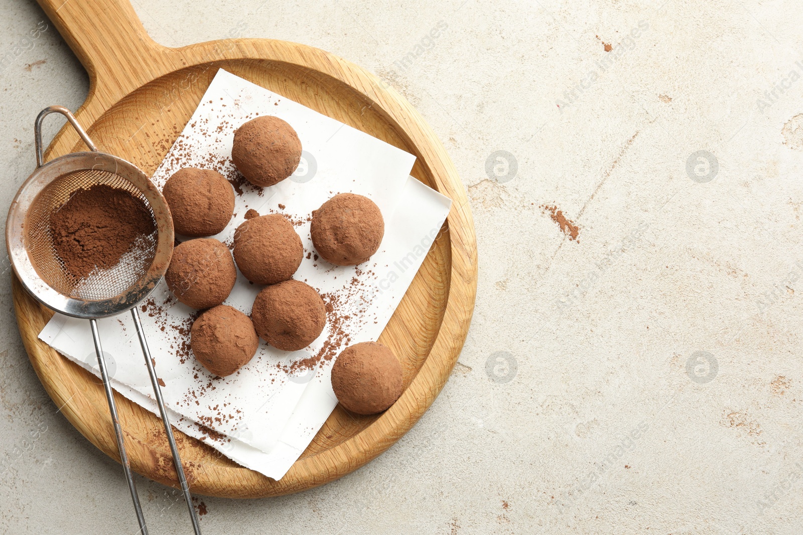 Tasty chocolate candies with cocoa powder and strainer on light table, top view. Space for text Photo of Tasty chocolate candies with cocoa powder and strainer on light table, top view. Space for text