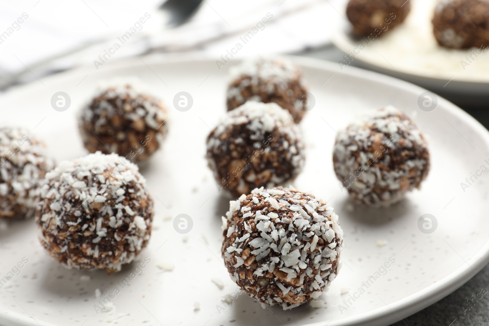 Tasty chocolate candies with nuts and coconut flakes on grey table, closeup Photo of Tasty chocolate candies with nuts and coconut flakes on grey table, closeup