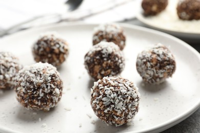 Photo of Tasty chocolate candies with nuts and coconut flakes on grey table, closeup