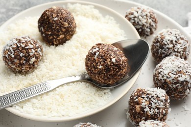 Photo of Making tasty chocolate candies with coconut flakes at grey table, closeup