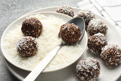 Photo of Making tasty chocolate candies with coconut flakes at grey table, closeup