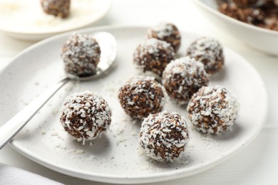 Photo of Tasty chocolate candies with nuts and coconut flakes on white table, closeup