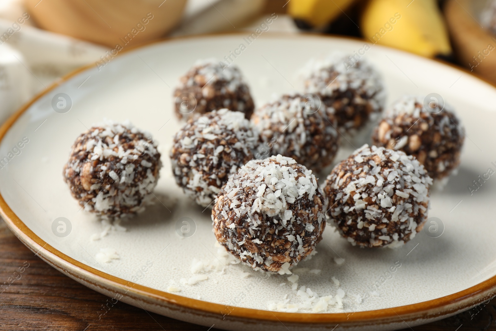 Tasty chocolate candies with nuts and coconut flakes on wooden table, closeup Photo of Tasty chocolate candies with nuts and coconut flakes on wooden table, closeup