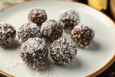 Photo of Tasty chocolate candies with nuts and coconut flakes on table, closeup