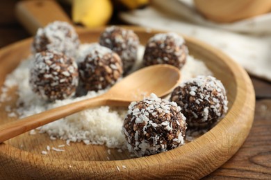 Photo of Tasty chocolate candies with nuts and coconut flakes on wooden table, closeup