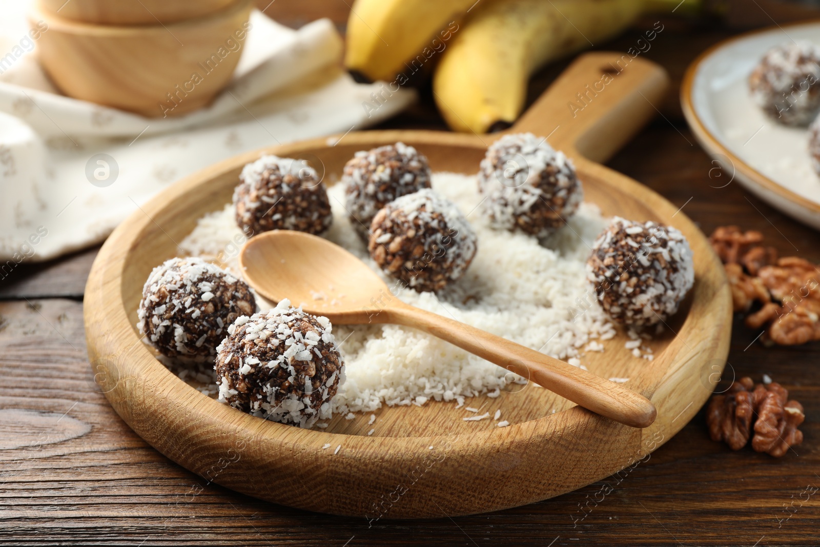 Tasty chocolate candies with nuts and coconut flakes on wooden table, closeup Photo of Tasty chocolate candies with nuts and coconut flakes on wooden table, closeup