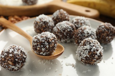 Photo of Tasty chocolate candies with nuts and coconut flakes on table, closeup