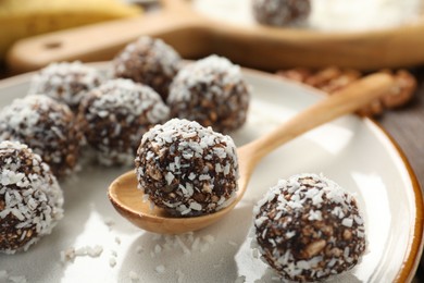 Photo of Tasty chocolate candies with nuts and coconut flakes on table, closeup