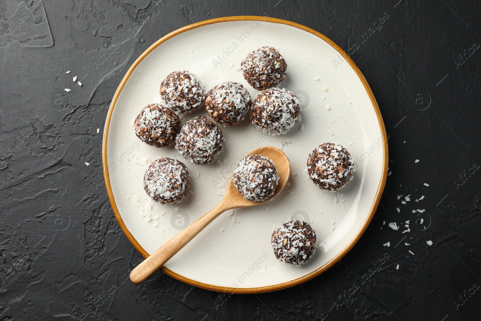 Tasty chocolate candies with nuts and coconut flakes on black table, top view Photo of Tasty chocolate candies with nuts and coconut flakes on black table, top view