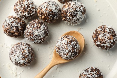 Photo of Tasty chocolate candies with nuts and coconut flakes on plate, top view