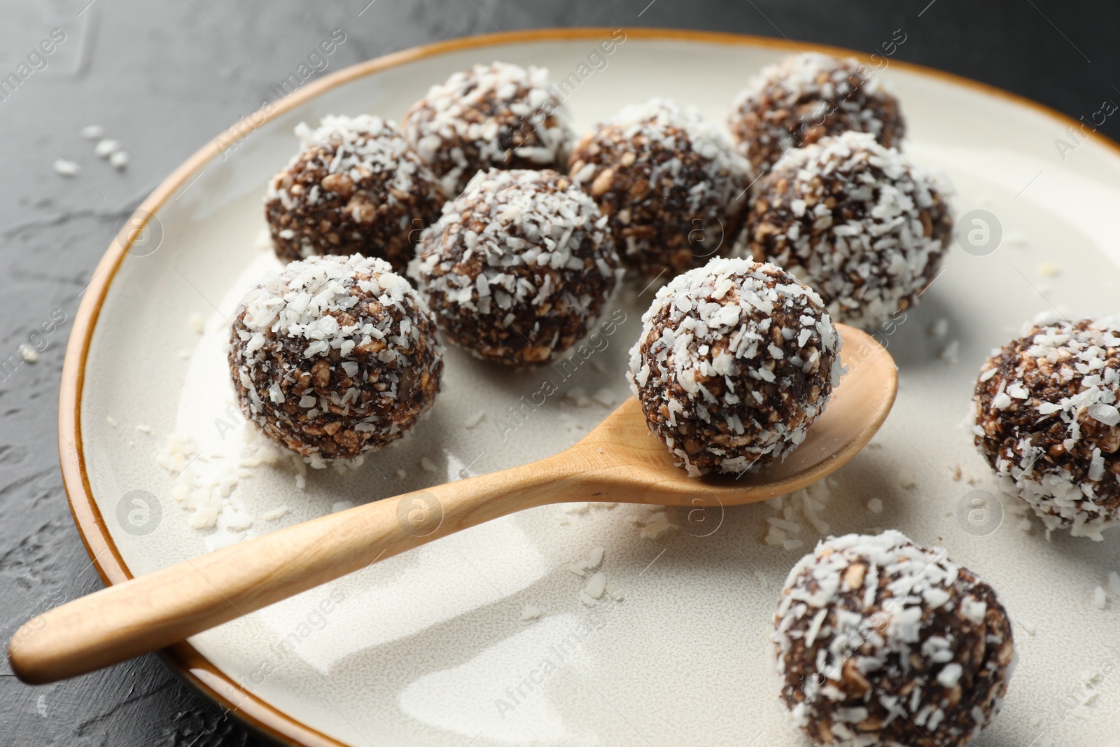 Tasty chocolate candies with nuts and coconut flakes on black table, closeup Photo of Tasty chocolate candies with nuts and coconut flakes on black table, closeup