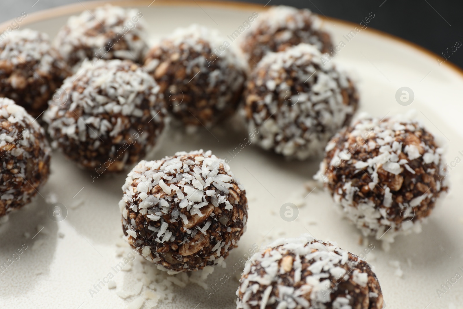 Photo of Tasty chocolate candies with nuts and coconut flakes on plate, closeup