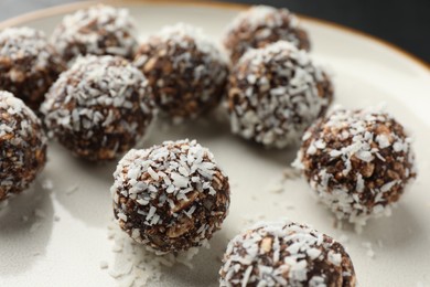 Photo of Tasty chocolate candies with nuts and coconut flakes on plate, closeup